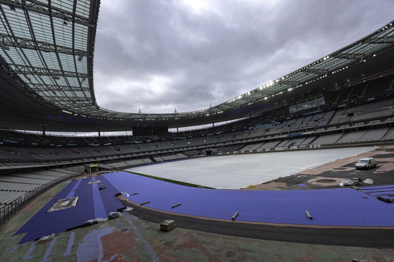 The purple athletics track at the Olympic Stadium, currently known as Stade de France, is being installed, in Saint-Denis, north of Paris, Tuesday, April 9, 2024. The Olympic Stadium will host the athletics events at the Paris 2024 Olympic Games. (AP Photo/Aurelien Morissard)