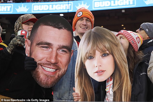 Fans hold large pictures of Travis Kielce and Taylor Swift during an NFL game on December 31