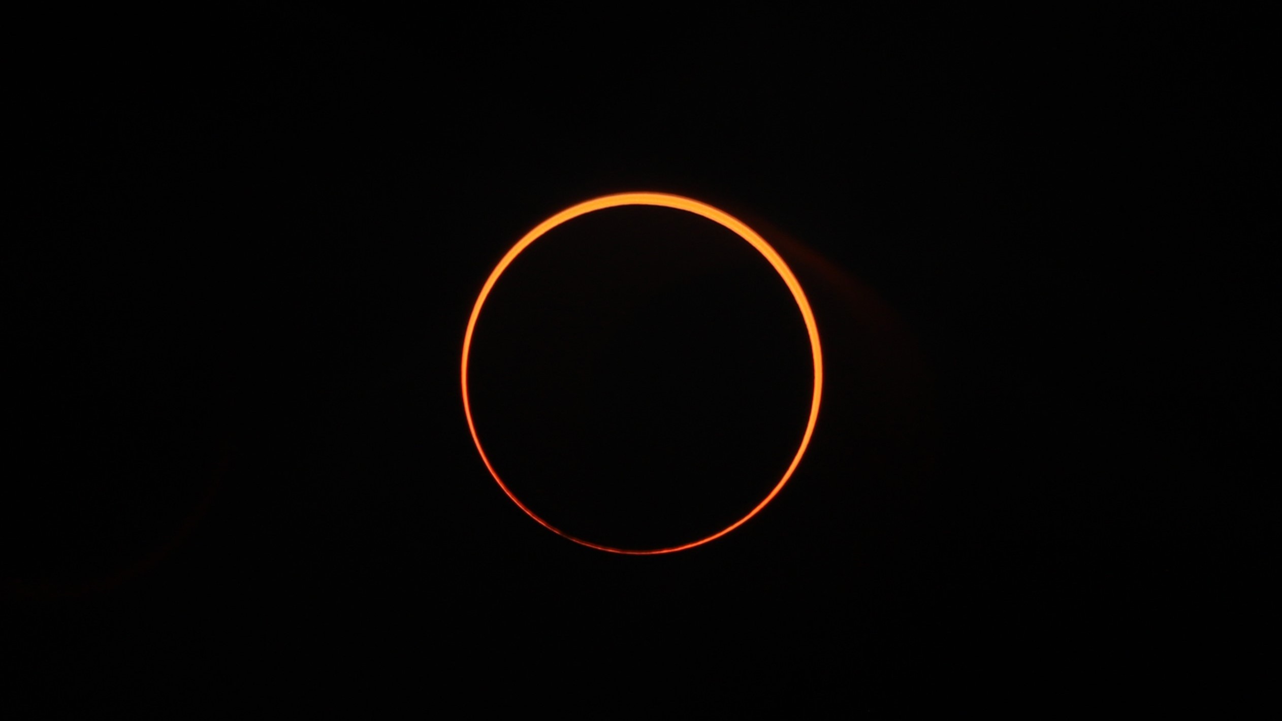 sun appears as an orange ring against a black sky.