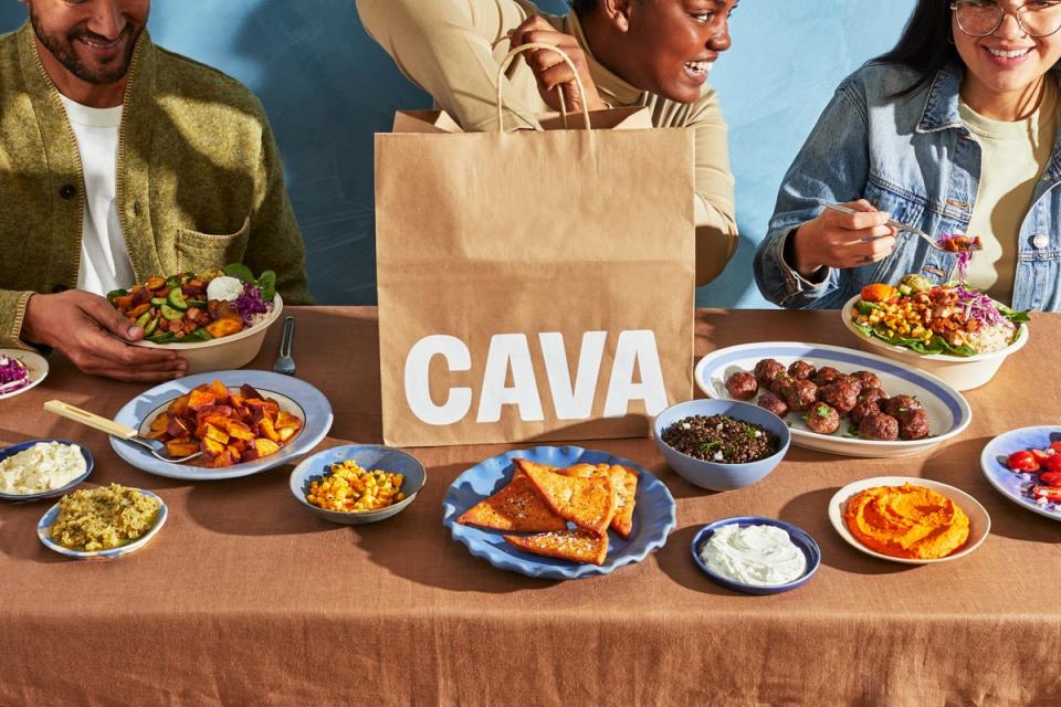 A Cava to-go bag with several dishes from the restaurant on a table